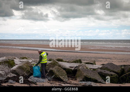 ein Hygiene-Arbeiter sammelt Müll vom Strand entfernt Stockfoto