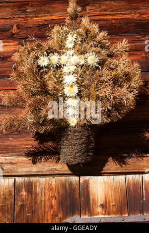 Retro-Dekoration der Alphütte, hergestellt aus Trockenblumen in Form ein Kreuzes. Bild im Freien an einem sonnigen Tag. Stockfoto