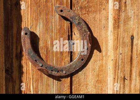 Rostige Hufeisen auf alten hölzernen Hintergrund. Bild im Freien an einem sonnigen Tag. Stockfoto
