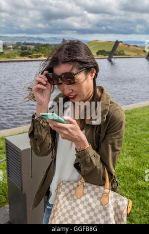 Asiatische Frau liest Text auf Handy, asiatische Frau, Lesen von Text, Handy, Artesa Weinberge und Weinkeller, Carneros region, Napa Valley, Kalifornien Stockfoto