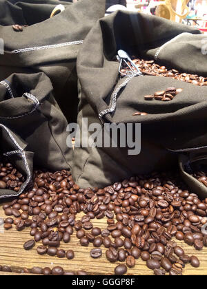 Kaffeebohnen auf Taschen über rustikale Holz Hintergrund Stockfoto