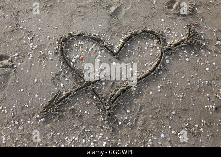 Herz-Symbol mit Pfeil gezeichnet am Strand Stockfoto