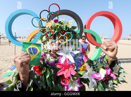 Ein Mann bedeckt in Blumen posiert für ein Foto vor der Olympischen Ringe an der Copacabana, Rio De Janeiro, Brasilien. Stockfoto