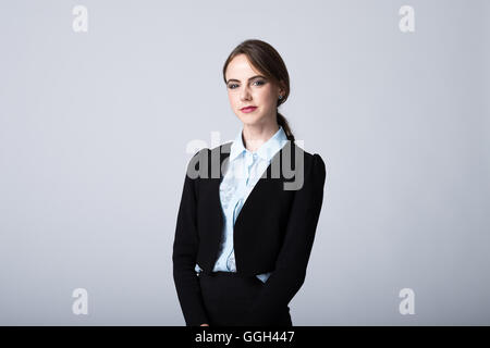 Eine selbstbewusste Profi in einem schwarzen Business-Anzug schaut mit einem rätselhaften Lächeln in die Kamera. Kopierbereich an beiden Seiten des Betreffs Stockfoto
