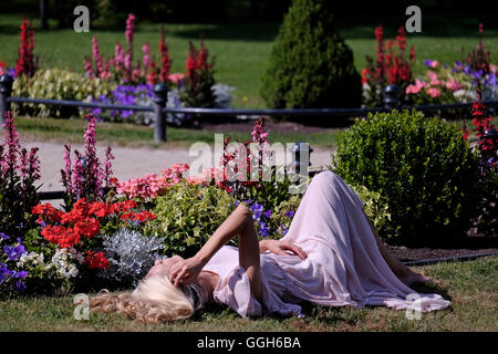 Die junge Litauerin liegt auf dem Rasen im Botanischen Garten an der Nordseite des Neorenaissance-Stils des 18. Jahrhunderts, Tiskeviciai, Tiskevicius-Palast oder Tyszkiewicz-Palast im Badeort Palanga, Litauen Stockfoto