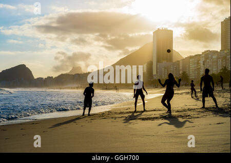 RIO DE JANEIRO - 30. Oktober 2015: Silhouetten der Brasilianer spielen Altinho Beach-Fußball in einem Kreis am Strand der Copacabana. Stockfoto