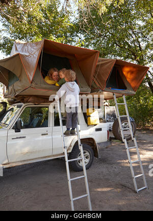 Jungs stehen auf einer Leiter, einem Dachzelt auf einen Geländewagen, Nata, Nxai Pan National Park, Botswana Stockfoto