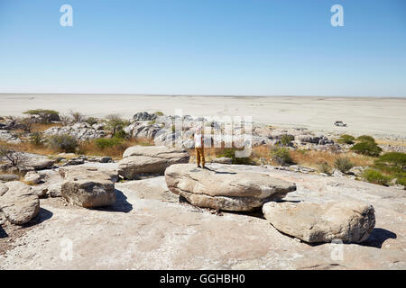 Frau steht auf einem Felsen bei der Suche über Salzwüste, Kubu Island, Makgadikgadi Pans Nationalpark, Botswana Stockfoto