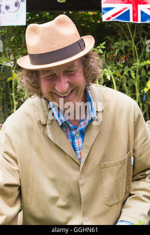 Fröhlicher Stallbesitzer, der im Juli auf dem Columbia Road Flower Market, London, Großbritannien, Geschäfte macht Stockfoto