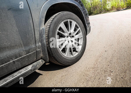 Nicht identifizierbare SUV-Auto-Fragment. Rad mit Leichtmetall-Disc auf Landstraße im Sommer, Nahaufnahme Foto Stockfoto