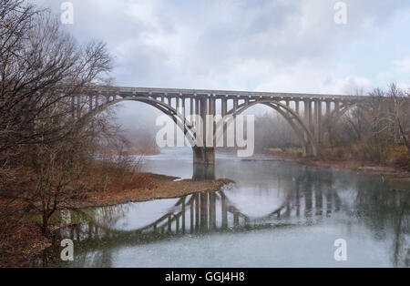 Eine symmetrische Reflexion, eine Fahrbahn Brücke an einem Misty späten Herbst Morgen über Little Miami River im südwestlichen Ohio, USA Stockfoto