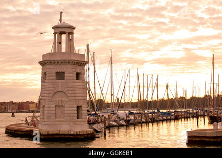 Kleiner Leuchtturm am Eingang der Marina Isola di San Giorgio Maggiore Insel entlang Bacino di San Marco bei Sonnenaufgang, Veni Stockfoto