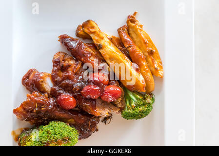 Schweinefleisch Rippe gegrillte und gebratene Kartoffelspalten auf weißen Teller mit Sauce und Gemüse, Gourmet-Küche. Stockfoto
