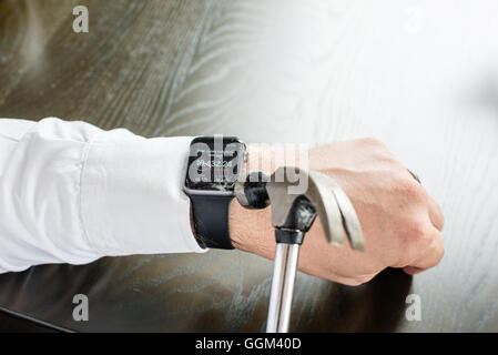 Ostfildern, Deutschland - 31. Juli 2016: Ein Geschäftsmann trägt ein weißes Hemd ist die Apple Watch am Handgelenk mit einem Hamm zu zerstören Stockfoto