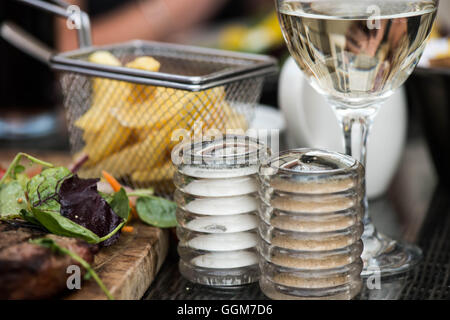 Korb der Fried Chips oder Pommes Frites, mit Glas kühlen Weißwein, Salz und Pfeffer und keine Leute am Tisch oben einstellen Stockfoto