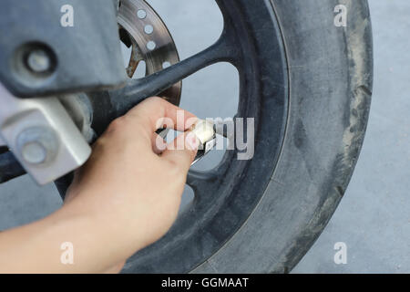 Hand des Menschen einem Wind in die Räder des Motorrades füllen diese Wartung vor der Abreise Reisen. Stockfoto