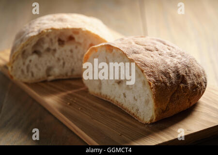 Hälften des frischen Ciabatta auf Oliven Schneidebrett Stockfoto