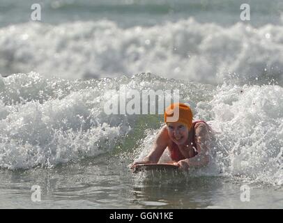 Ältere Frau genießt Bodyboarden Polzeath Strand, Cornwall, UK Stockfoto