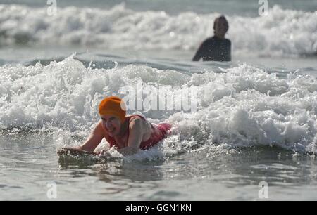 Ältere Frau genießt Bodyboarden Polzeath Strand, Cornwall, UK Stockfoto