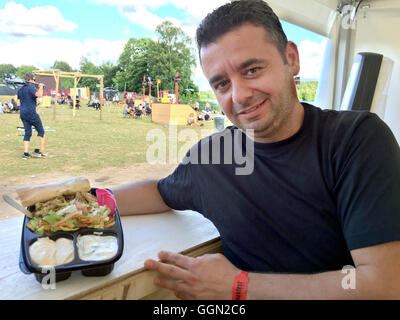 Skanderborg, Dänemark. 5. August 2016. Syrischer Flüchtling Haval Zahabi steht ein Imbiss-Stand und zeigt die syrischen Reisgericht 'Kabsa' beim 'Smukfest' Music Festival in Skanderborg, Dänemark, 5. August 2016. Foto: JULIA WAESCHENBACH/Dpa/Alamy Live News Stockfoto