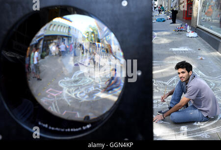 Umgangsverweigerung, Deutschland. 6. August 2016. 3D Artist Dogan Sitki aus der Türkei wird Kreide ein drei-Dimensioanl Bild eines Weckers auf dem Bürgersteig in der Fußgängerzone am Street Art Festival in Umgangsverweigerung, Deutschland, 6. August 2016 gezeichnet. Die dicken Linse gibt Besuchern die Möglichkeit, die Straße Bild räumlich betrachtet. Rund 40 Straßenmaler, 3D-Künstler und Bodypainter aus aller Welt nehmen an der 6. International Street Art Festival auf der Jade Bucht Teil. Foto: INGO WAGNER/Dpa/Alamy Live News Stockfoto