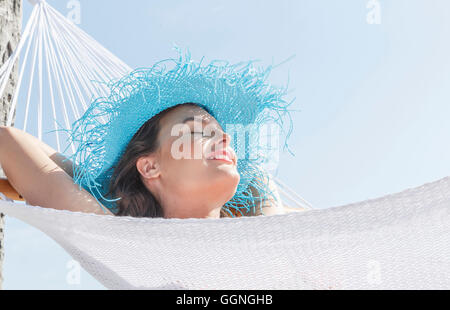 Kaukasische Frau mit Sonnenhut in Hängematte Stockfoto