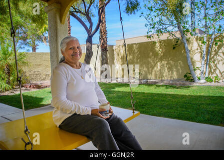 Schwingen Sie ältere indische Frau Kaffee trinken auf Terrasse Stockfoto