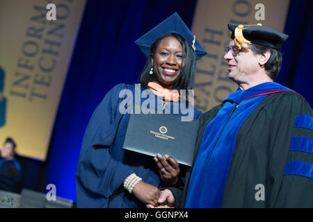 Graduierung Kandidat in Mütze und Mantel erhält Diplom an Western Governors University Abschlussfeier in Orlando, FL Stockfoto