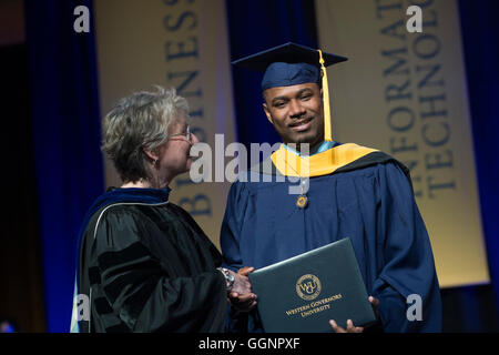 Graduierung Kandidat in Mütze und Mantel erhält Diplom an Western Governors University Abschlussfeier in Orlando, FL Stockfoto