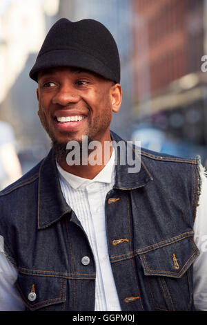 Lächelnder afroamerikanische Mann mit Hut und Denim Weste Stockfoto