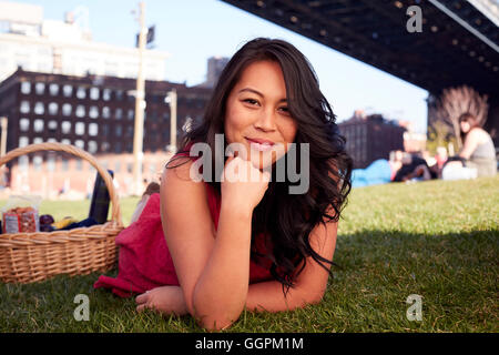 Pacific Islander Frau Verlegung auf Rasen mit Picknick-Korb Stockfoto