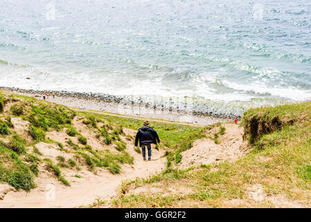 Kaseberga, Schweden - 1. August 2016: Echte Menschen im Alltag. Junger Erwachsener Mann zu Fuß oder Abrutschen einen Sandweg auf einem Hügel Stockfoto