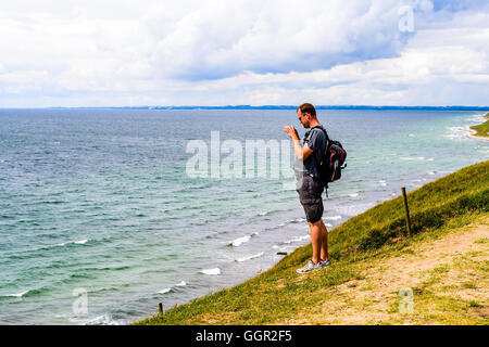 Kaseberga, Schweden - 1. August 2016: Mann stand auf Meer Hügel mit dem Landschaft fotografieren mit seinem Handy. Echte li Stockfoto