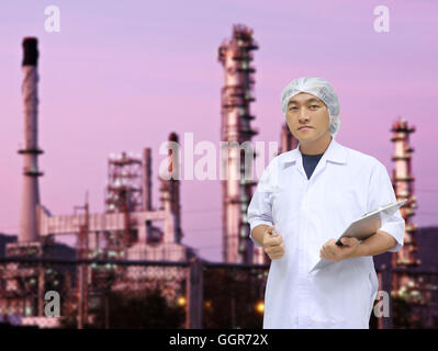 Ein Mann in weißen großen Mantel Uniform und Ölraffinerie der Hintergrund für das Konzeptdesign Quality Inspection Business. Stockfoto