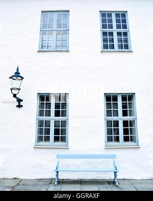 Blauen Fenstern, eine blaue Sitzbank und eine Straßenlaterne. Weiße Wand sauber. Stockfoto