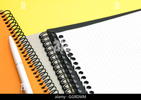 Schwarz und orange Notizblöcke, Blatt mit Stift auf gelben Schreibtisch-Hintergrund Stockfoto