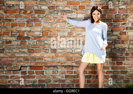 Porträt des jungen stets gut gelaunte Frau gegen eine Mauer. Sonniger Tag. Stockfoto