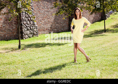 Attraktive Frau im gelben Kleid verbringt viel Zeit im Park. Stockfoto