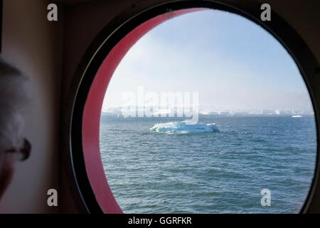 Ein Passagier durch Kreuzfahrt Schiffs Bullauge Kabinenfenster auf Eisberge von Ilulissat Eisfjord in der Disko-Bucht. Westgrönland Stockfoto