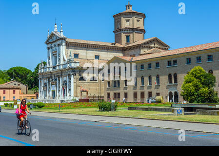 Radfahrer kreuzen Via di Roma von Ravenna mit Basilika von Santa Maria in Porto im Hintergrund. Emilia-Romagna. Italien. Stockfoto