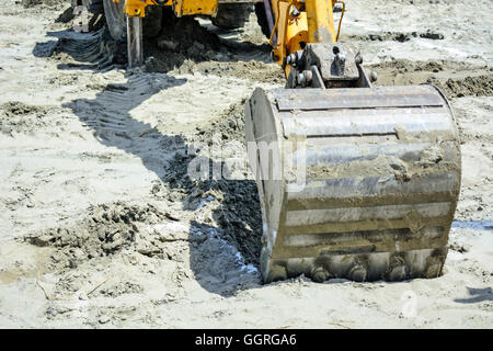 Bagger in einer Situation gräbt Löcher in den sandigen Boden. Stockfoto