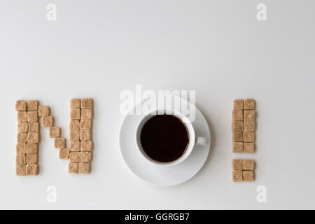 Würfelzucker und Tasse Kaffee als Wort nicht auf weißem Hintergrund angeordnet. Ansicht von oben. Diät-Unhealty-süße sucht-Konzept Stockfoto