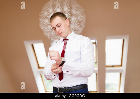 Der Bräutigam legt seine Hand auf die Uhr Stockfoto