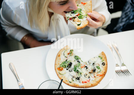 Kaukasische Frau Essen Stück Pizza im restaurant Stockfoto