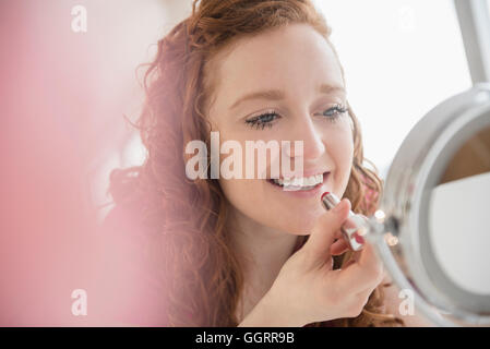 Kaukasische Frau Auftragen von Lippenstift im Spiegel Stockfoto