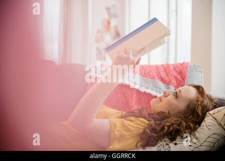 Kaukasische Frau Verlegung auf Sofa Buch Stockfoto