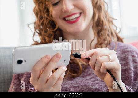 Kaukasische Frau mit Schnur Mobiltelefon verbinden Stockfoto