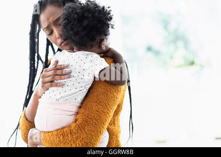 Schwarze Frau halten und beruhigend Tochter Stockfoto