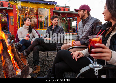 Paare, trinken Cocktails und Bier im Freien am Schaufenster Lagerfeuer Stockfoto