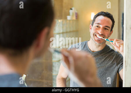 Hispanic Mann Zähneputzen im Spiegel Stockfoto